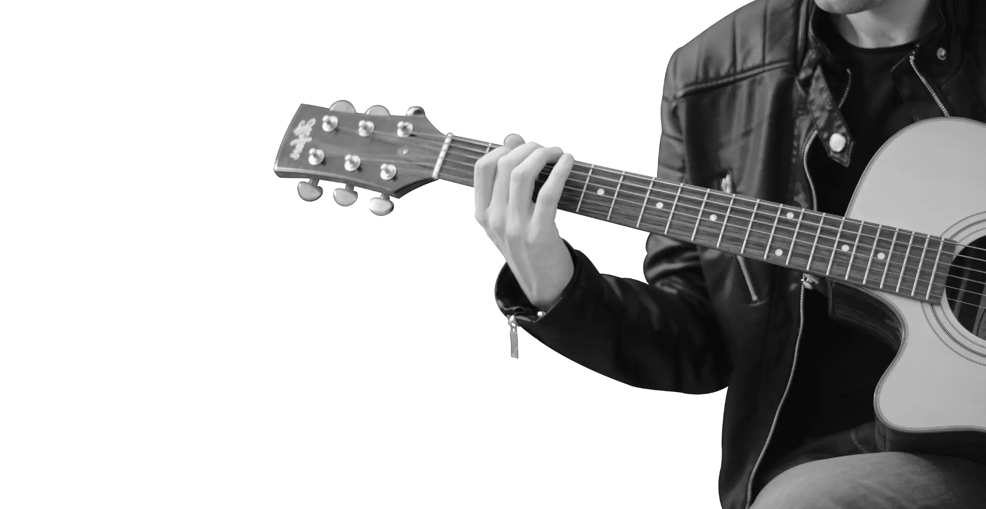 In black and white, partially a person wearing a leather jacket, black shirt and jeans, sitting down and playing a guitar.